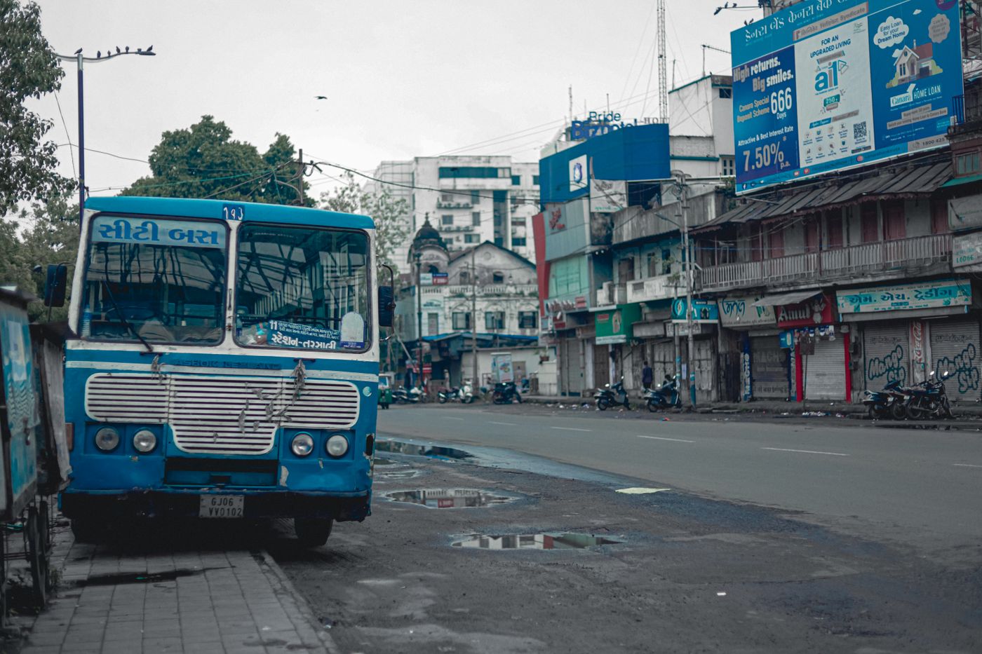 A city bus on an Indian high street, with shop signs and a billboard